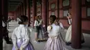 Pengunjung mengenakan pakaian tradisional Korea, Hanbok sambil berpose di istana Gyeongbokgung, Seoul, Rabu (26/9). Korea Selatan sedang menikmati hari terakhir dari liburan Chuseok atau Hari Thanksgiving. (AFP PHOTO / Ed JONES)