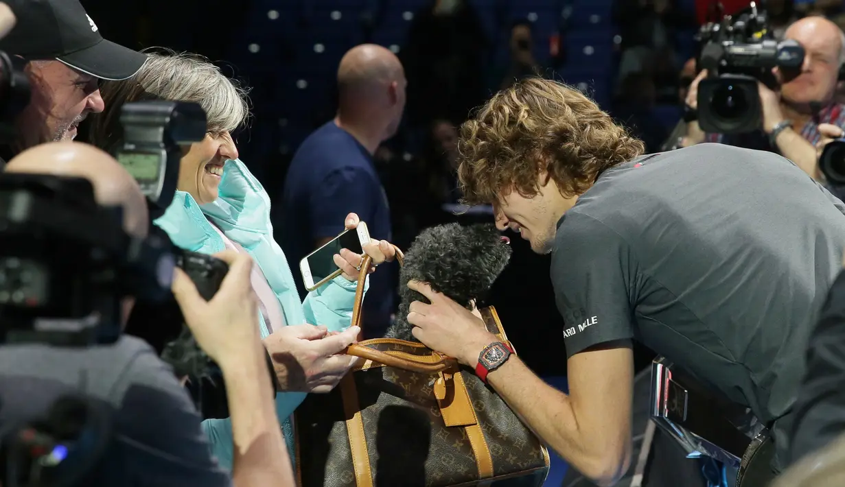 Petenis Jerman, Alexander Zverev mencium anjing setelah mengalahkan Novak Djokovic pada laga puncak ATP Finals 2018 di O2 Arena, London, Senin (19/11). Zverev secara mengejutkan menumbangkan petenis peringkat 1 dunia dengan 6-4, 6-3. (AP/Tim Ireland)