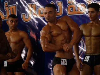 Kontestan memamerkan otot mereka saat tampil di atas panggung kompetisi binaraga lokal di Kota Gaza pada Minggu (15/9/2019). Kompetisi ini diikuti oleh sejumlah pria Palestina. (AP Photo/Hatem Moussa)