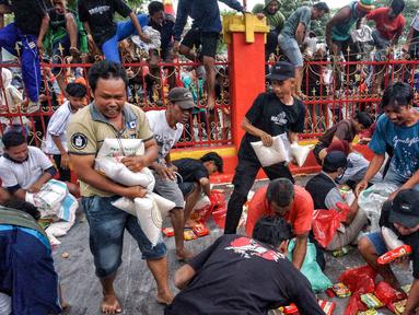 Orang-orang berebut untuk mendapatkan bahan makanan yang dibagikan kepada masyarakat umum selama Festival Hantu Lapar di Kuil Gie Yong Bio, Lasem, Jawa Tengah, pada 10 September 2025. (Foto: AFP)