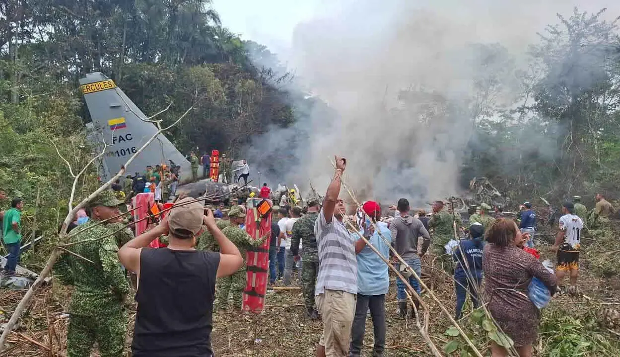 Orang-orang berdiri di sekitar pesawat kargo militer yang jatuh setelah lepas landas dari Puerto Leguizamo, Kolombia, sebuah kotamadya terpencil di provinsi Amazon Putumayo, Senin, 23 Maret 2026. Sebuah pesawat angkut militer milik Angkatan Udara Kolombia jatuh saat lepas landas di wilayah selatan Provinsi Putumayo. (MiPutumayo via AP)