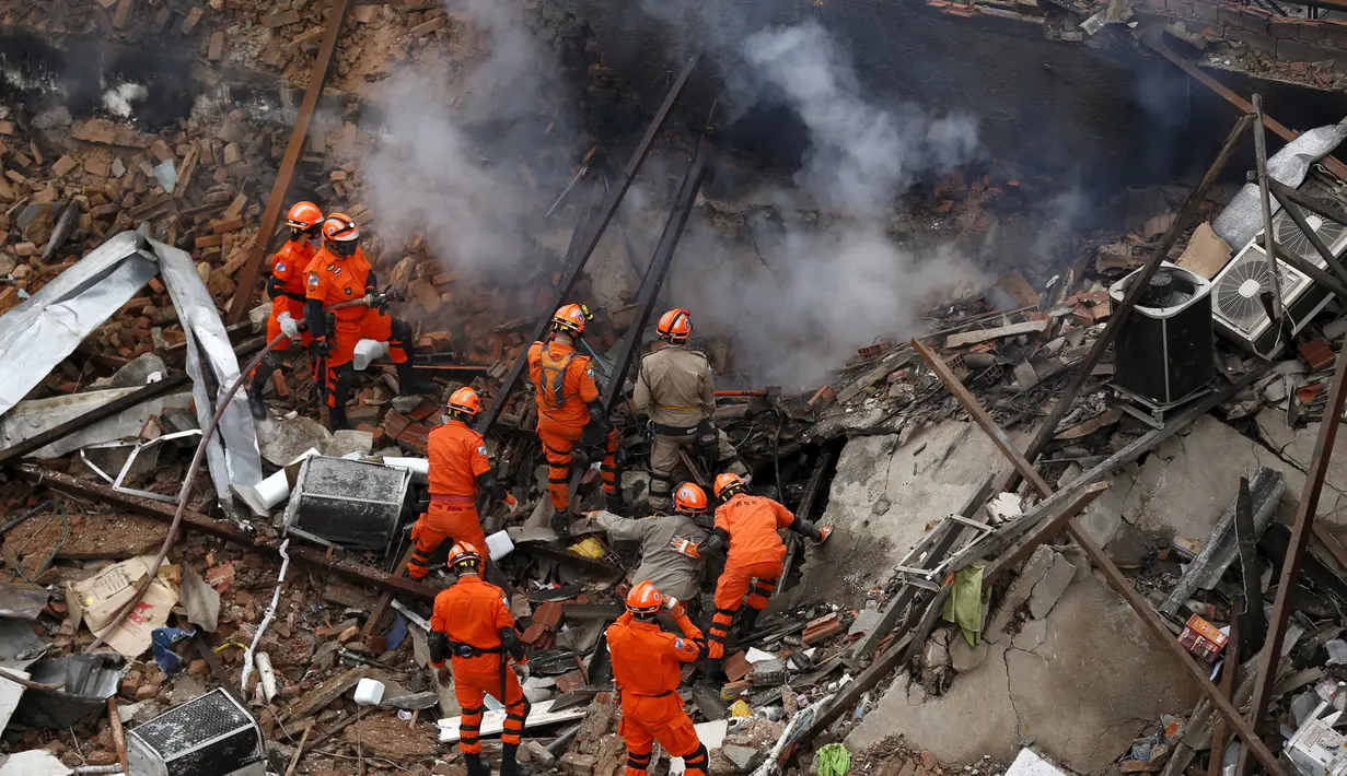 Petugas pemadam kebakaran dan penyelamat saat berupaya membersihkan reruntuhan bangunan yang hancur akibat ledakan yang terjadi Rio de Janeiro, Brasil, Senin (19/10/2015). Peristiwa ini menewaskan 7 orang dan lainnya cedera. (REUTERS/Pilar Olivares)
