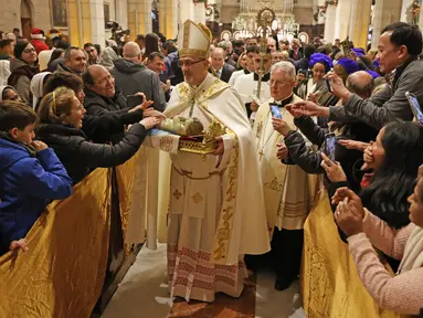 Patriark Latin Yerusalem, Pierbattista Pizzaballa memimpin Misa Malam Natal di Kompleks Gereja Kelahiran Yesus, Bethlehem, Tepi Barat, Minggu (25/12/2022). Setelah dua tahun tutup karena COVID-19, jemaat kembali menghadiri ibadah tersebut kendati jumlahnya tidak sebanyak sebelum pandemi. (Ahmad Gharabli/Pool Photo via AP)