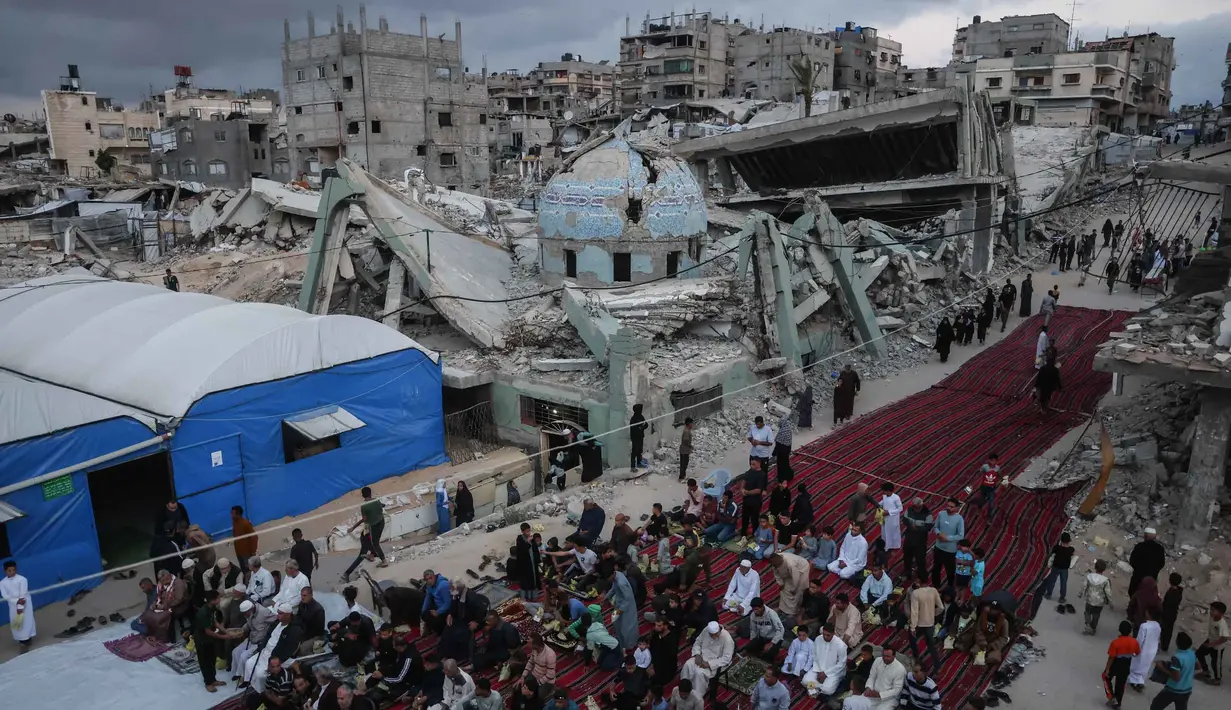 Warga Palestina berkumpul di jalan yang rusak parah untuk melaksanakan salat menandai dimulainya Idul Adha, Hari Raya Kurban, di Khan Yunis, Jalur Gaza Selatan, pada Rabu 27 Mei 2026. (BASHAR TALEB/AFP)