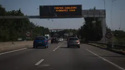 Tanda jalan bertuliskan "Panas Ekstrem, minum air", memperingatkan pengendara tentang prakiraan gelombang panas saat suhu udara melebihi 42 derajat celsius di lingkar jalan di Nantes, Senin (18/7/2022). Peramal cuaca menempatkan 15 departemen di sebagian besar sisi barat Prancis ke status siaga tertinggi untuk suhu ekstrem. (Loic VENANCE / AFP)