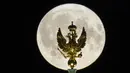 Bulan purnama terbesar atau supermoon muncul di atas patung perunggu berlapis emas elang berkepala dua, lambang negara Rusia, yang dipasang di atas Menara Telegraf Museum State Hermitage di St. Petersburg, Senin (19/8/2024). (AP Photo/Dmitri Lovetsky)