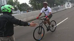 Petugas mengarahakan pesepeda non road bike saat memasuki JLNT Kampung Melayu-Tanah Abang, Jakarta, Minggu (30/5/2021). Uji coba kedua ini bertujuan kembali mendapatkan masukan dari penggiat sepeda secara lengkap baik dari sisi operasional maupun teknis kedepannya. (Liputan6.com/Herman Zakharia)