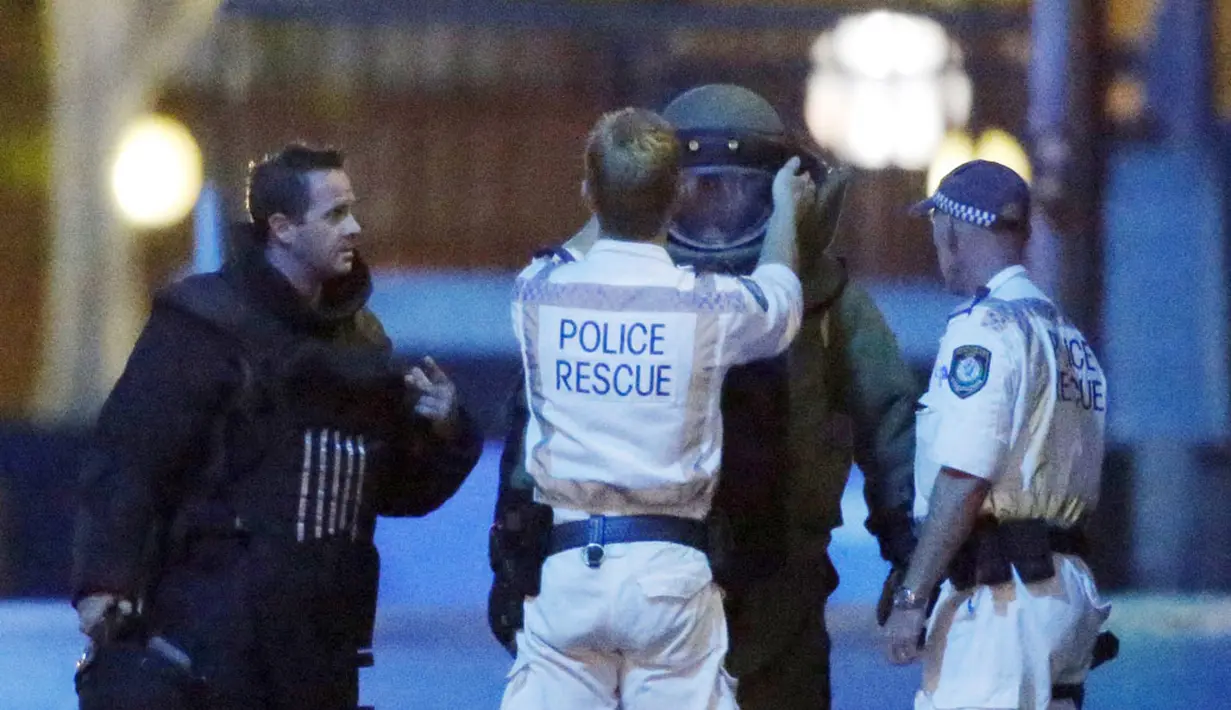 Seorang polisi membantu memakaikan pakaian lapis baja di dekat Kafe Lindt di Martin Place, Sydney (16/12/2014). Seorang pria bersenjata masuk ke Kafe Lindt dan menyandera beberapa orang yang berada di dalam kafe tersebut. (REUTERS/Jason Reed)