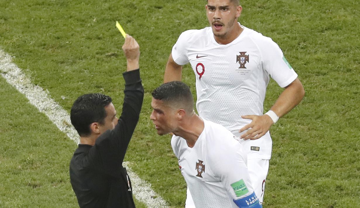 Cristiano Ronaldo menerima kartu kuning dari wasit Cesar Ramos asal Meksiko saat melawan Uruguay pada laga 16 besar Piala Dunia 2018 di Fisht Stadium, Sochi, Rusia, (30/6/2018). Portugal kalah 1-2 dari Uruguay. (AP/Darko Vojinovic)