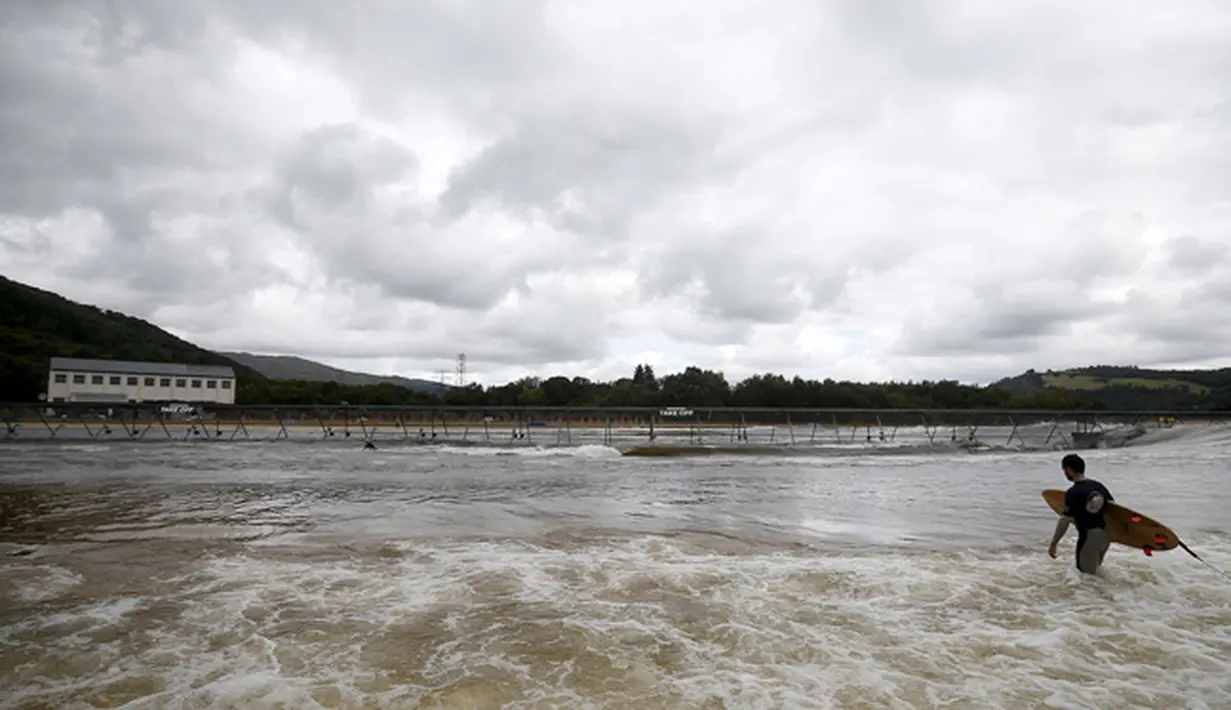 Seorang pria tampak berjalan untuk mencoba keseruan berselancar di Surf Snowdonia, Conwy, North Wales, Kamis (3/9/2015).  Danau buatan ini menghabiskan dana hingga ratusan miliar. (REUTERS/Andrew Yates) 