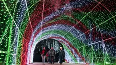 Pengunjung berjalan melalui terowongan cahaya pada pertunjukan cahaya Holiday Road di Calabasas, California, Amerika Serikat, 10 Desember 2021. Holiday Road digelar sepenuhnya setelah pandemi COVID-19 mengubah festival cahaya tahunan ini menjadi acara drive-thru tahun lalu. (AP Photo/Jae C.Hong)
