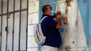 Seorang pria Palestina dengan masker mengunci tokonya saat pemberlakukan lockdown selama 48 jam di Jalur Gaza, Selasa (25/8/2020). Lockdown dan jam malam diberlakukan di wilayah jalur Gaza menyusul terkonfirmasinya kasus Covid-19 pertamanya di sebuah kamp pengungsian. (AP Photo/Hatem Moussa)