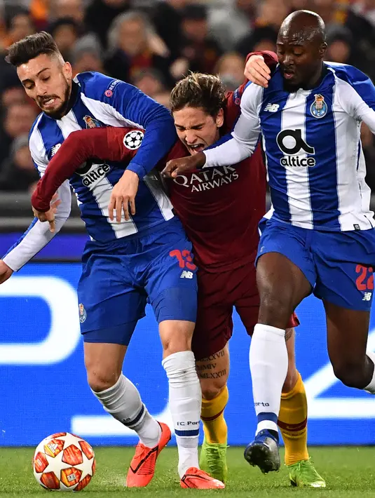 Gelandang AS Roma Nicolo Zaniolo (tengah) terjepit saat berusaha melewati pemain FC Porto Alex Telles dan Danilo Pereira dalam babak 16 besar Liga Champions di Stadion Olimpico, Roma, Italia, Selasa (12/2). AS Roma menang 2-1. (Alberto PIZZOLI/AFP)