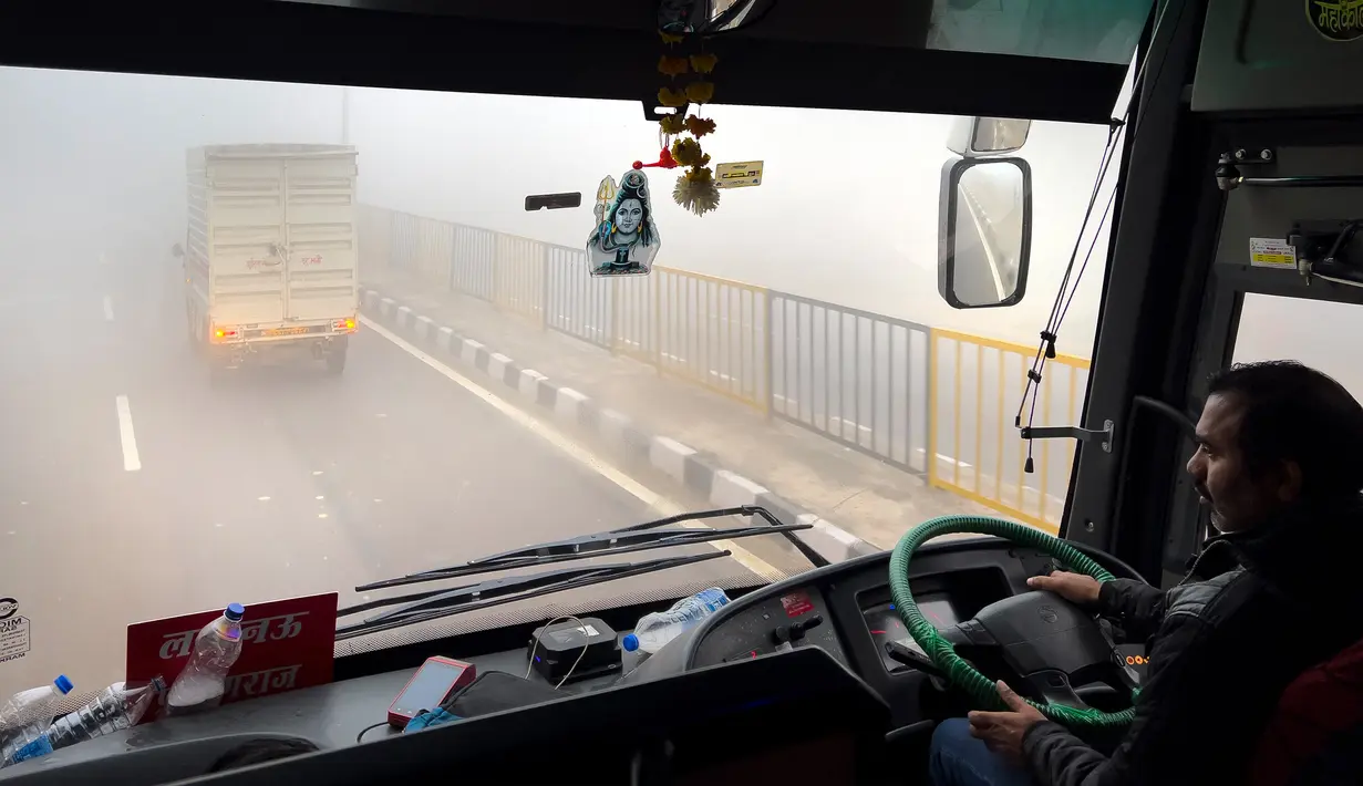 Seorang pengemudi bus mengemudi di tengah kabut asap pagi dekat Lucknow, India, Selasa (20/12/2022). India Utara mengalami kabut pertama musim ini dan diperkirakan akan berlangsung selama lima hari ke depan yang mengganggu transportasi kereta api, jalan raya, dan udara. (AP Photo/Rajesh Kumar Singh)