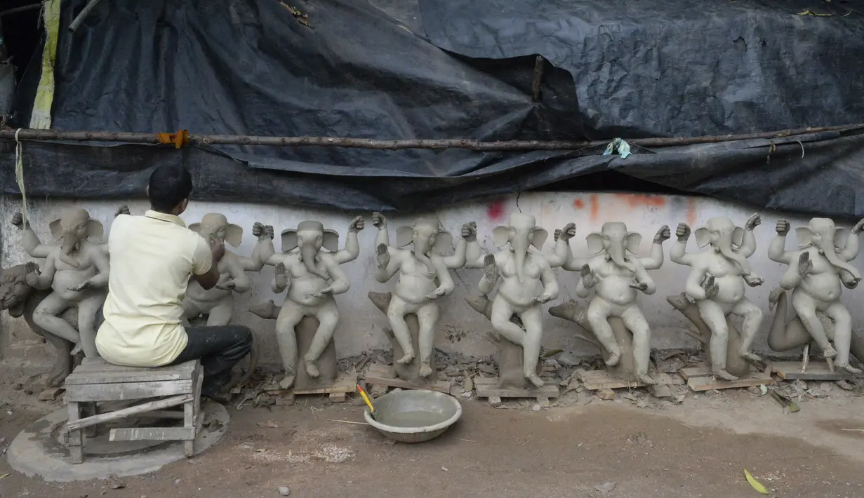 Perajin membuat patung Dewa Ganesha di sebuah bengkel di pinggiran Hyderabad, India, Rabu (18/8/2021). ​Patung ramah lingkungan yang dibuat jelang perayaan Ganesh Chaturthi tersebut dibuat dari lumpur, serat rami, dan bambu untuk mengurangi polusi air. (NOAH SEELAM/AFP)