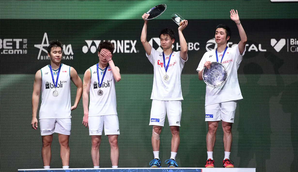 Pasangan Jepang Hiroyuki Endo/Yuta Watanabe dan pasangan Indonesia Kevin Sanjaya Sukamuljo/Marcus Fernaldi Gideon berdiri di podium usai laga final ganda putra All England 2020 di Birmingham, Inggris, Minggu (15/3/2020). Kevin/Marcus kalah dengan skor 18-21, 21-12, dan 19-21. (Oli SCARFF/AFP)