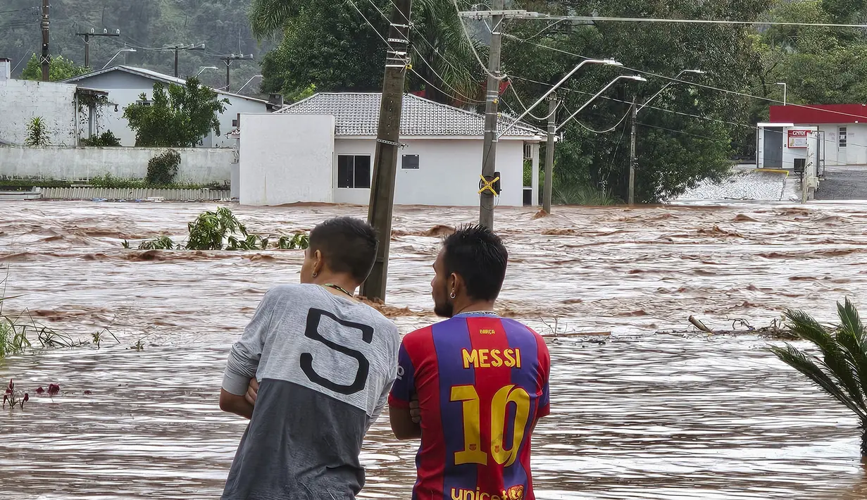 Orang-orang mengamati jalan yang banjir setelah hujan lebat di Encantado, Rio Grande do Sul, Brasil, Rabu (1/5/2024). (Photo by Gustavo Ghisleni / AFP)
