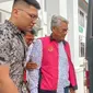 Mantan Bupati Kuansing Sukarmis digiring penyidik ke mobil tahanan setelah menjadi tersangka korupsi hotel Kuansing. (Liputan6.com/M Syukur)