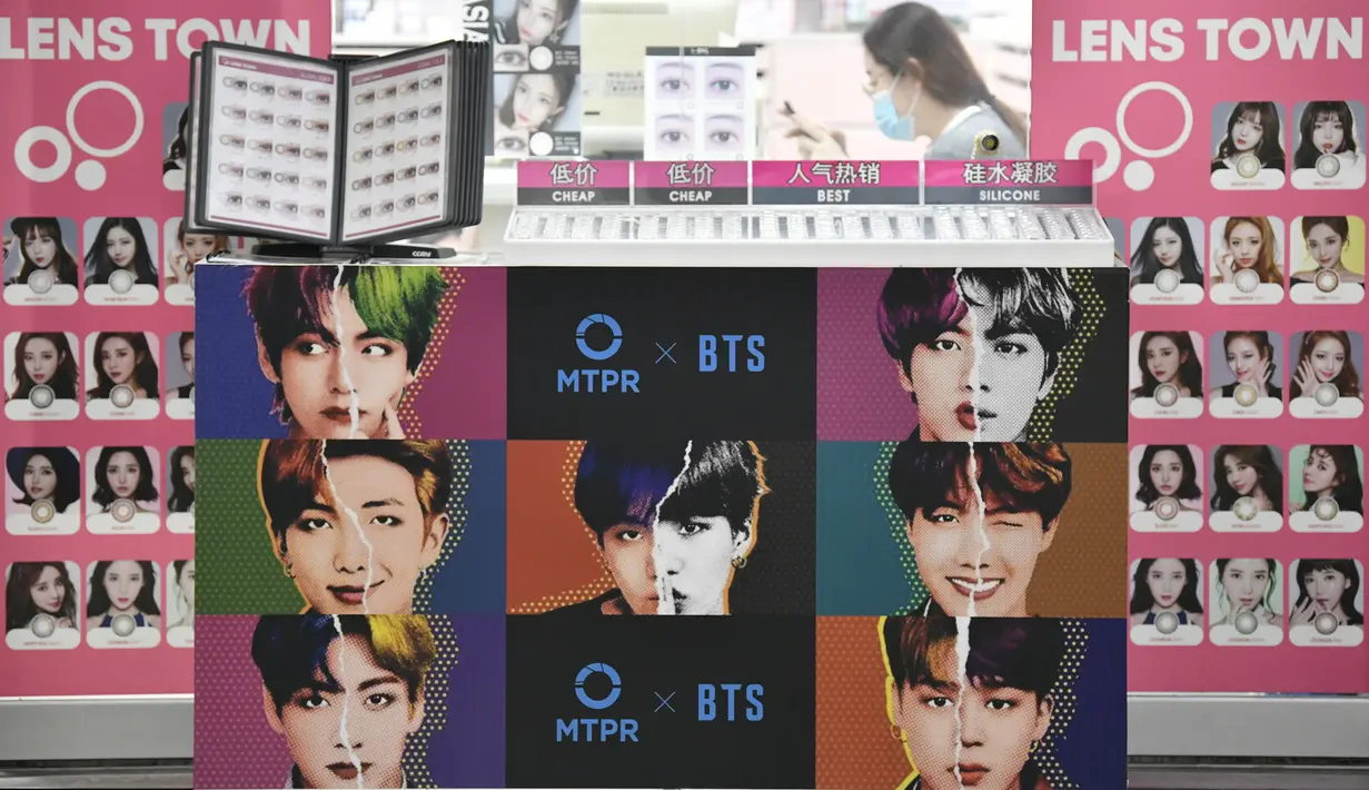 Sebuah poster komersial yang menunjukkan anggota boyband K-pop, BTS, terlihat di luar toko lensa kontak di Seoul, Selasa (1/9/2020). Bangtan Boys (BTS) menjadi artis Korea Selatan pertama yang berhasil menempati puncak Billboard Hot 100 dengan lagu Dynamite. (Jung Yeon-je/AFP)