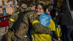 Seorang warga Kherson memeluk anggota pasukan pertahanan Ukraina di Kherson, Ukraina selatan, Senin (14/11/2022). Perebutan kembali Kherson adalah salah satu keberhasilan terbesar Ukraina dalam hampir sembilan bulan sejak invasi Moskow. (AP Photo/Bernat Armangue)