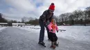Seorang ibu mengajari putrinya berseluncur di gelanggang es di Doorn, Belanda, Selasa (9/2/2021). Dengan perkiraan suhu beku selama lebih dari seminggu di Belanda, demam es melanda Negeri Kincir Angin tersebut. (AP Photo/Peter Dejong)