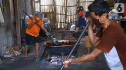 Pekerja mengaduk adonan dodol di pabrik dodol Betawi Mugi Jaya, Cilenggang, Tangerang Selatan, Rabu (13/5/2020). Produksi dodol selama pandemi Covid-19 menggunakan dua tungku. (Liputan6.com/Fery Pradolo)