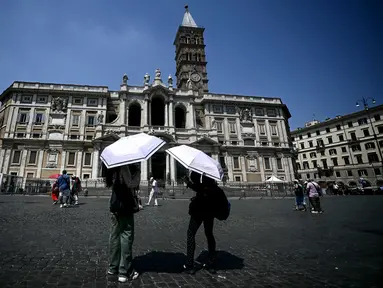 Dua orang membuka payung untuk melindungi diri dari terik matahari saat berdiri di depan Basilika Santa Maria Maggiore di pusat kota Roma pada 11 Agustus 2025. (Filippo MONTEFORTE/AFP)