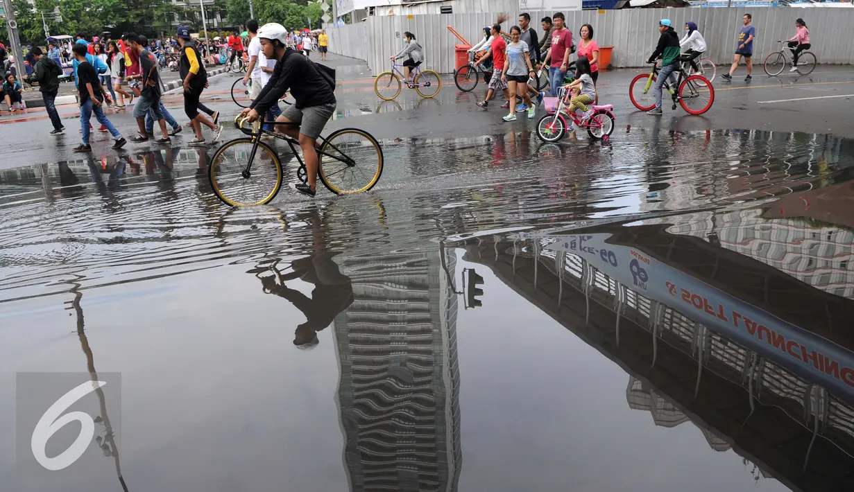 Kegiatan Car Free Day di Jakarta tetap ramai walau hujan mengguyur sejak semalam, Minggu (24/1/2016). Genangan air masih tersisa di jalan sekitar kawasan Car Free Day. (Liputan6.com/Helmi Affandi)