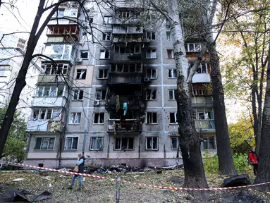 Penduduk setempat berjalan di sekitar gedung bertingkat mereka yang rusak akibat ledakan serangan pesawat tak berawak di Kyiv, pada 30 Oktober 2024. (Anatolii STEPANOV/AFP)