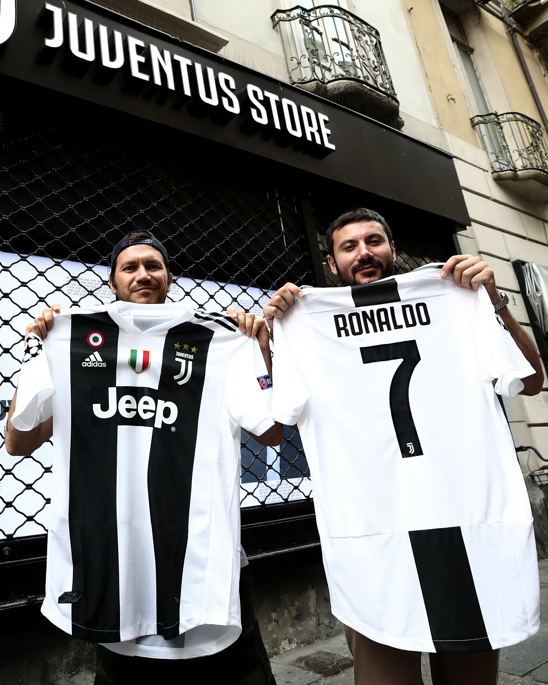 Suporter memperlihatkan jersey Juventus atas nama Cristiano Ronaldo di depan toko resmi klub di Turin, Selasa (10/7). Ronaldo akan diperkenalkan secara resmi ke publik sebagai pemain Juventus pada Senin depan. (AFP PHOTO / Isabella Bonottovv)