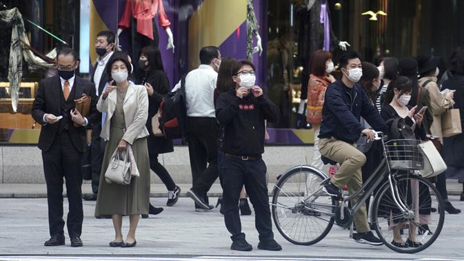 Orang-orang yang mengenakan masker untuk membantu mengekang penyebaran virus corona COVID-19 menunggu untuk menyeberang jalan di Tokyo, Jepang, Rabu (28/10/2020). Tokyo mengonfirmasi lebih dari 170 kasus virus corona COVID-19 baru pada 28 Oktober 2020. (AP Photo/Eugene Hoshiko)