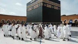 Penurunan biaya haji 2026 tetap dilakukan meski harga bahan bakar pesawat (avtur) sedang mengalami lonjakan signifikan. Tampak dalam foto, para calon jemaah haji Indonesia melakukan ritual tawaf mengelilingi replika Ka'bah, di Al Mahmudah Manasik Training Center (AMTC), sebuah fasilitas pelatihan haji yang menampilkan replika situs-situs ziarah utama, di Tangerang Selatan pada 5 April 2026. (YASUYOSHI CHIBA/AFP)