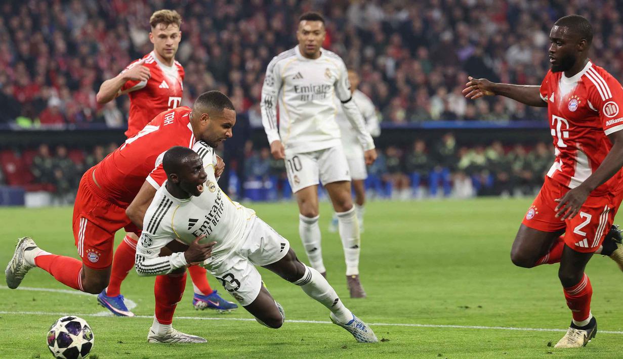 Hasil ini membuat skor agregat menjadi 6-4 untuk kemenangan Die Roten setelah menang 2-1 di laga leg pertama di Santiago Bernabeu, Madrid, pekan lalu. Tampak dalam foto, bek Bayern Munchen asal Jerman, Jonathan Tah (kiri), berebut bola dengan  bek Real Ferland Mendy (Real Madrid) saat pertandingan leg kedua perempat final Liga Champions 2025/2026 di Allianz Arena, Jerman Selatan, pada Rabu 15 April 2026 waktu setempat atau Kamis (16/4/2026) dini hari WIB. (Alexandra BEIER/AFP)