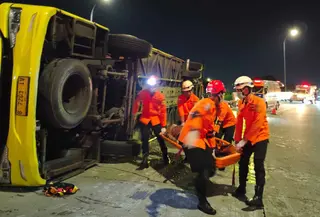 Bus diduga melaju dengan kecepatan tinggi sebelum menabrak pembatas jalan di tikungan jalur penghubung dan terguling hingga atap kabin ringsek. Tampak dalam foto, personel dari Badan Nasional Pencarian dan Pertolongan (Basarnas) Semarang melakukan evakuasi korban kecelakaan bus di Exit Tol Krapyak Kota Semarang, Jawa Tengah, Senin (22/12/2025) dini hari. (Foto: Basarnas Semarang)