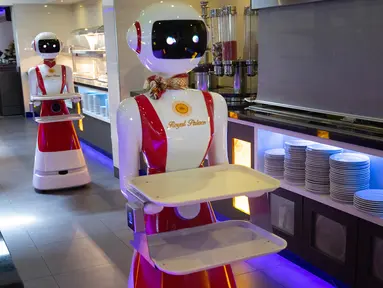Leah Hu (kiri) menunjukkan penggunaan robot pengganti pelayan sebagai bagian dari uji coba langkah-langkah aturan jaga jarak di restoran keluarga Royal Palace, Belanda, 27 Mei 2020. Robot ini bertugas menyapa pelanggan, menyajikan makanan dan minuman dan mengembalikan alat makan. (AP/Peter Dejong)