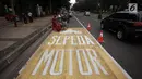 Pekerja menyelesaikan pengecatan rambu jalur kuning khusus sepeda motor di Jalan Medan Merdeka, Jakarta, Selasa (16/1).  Seperti diketahui, Mahkamah Agung (MA) membatalkan pergub larangan sepeda motor melintas di kawasan itu. (Liputan6.com/Arya Manggala)