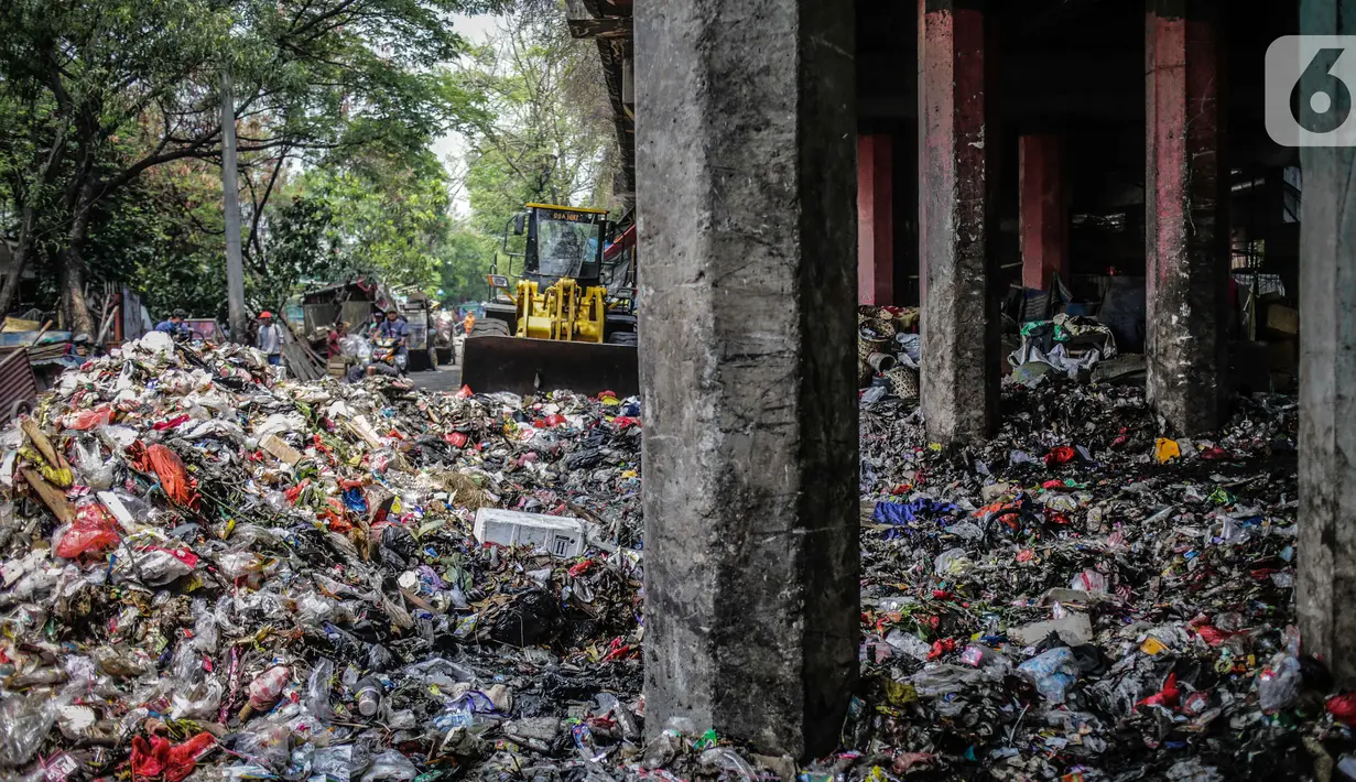 Petugas PPSU menggunakan kendaraan alat berat untuk mengangkut tumpukan sampah di kolong tol Wiyoto Wiyono, Tanjung Priok, Jakarta, Selasa (5/11/2019). Kolong Tol Tol Wiyoto-Wiyono berubah menjadi tempat penampungan sampah rumah tangga dari tiga kelurahan di kawasan itu. (Liputan6.com/Faizal Fanani)