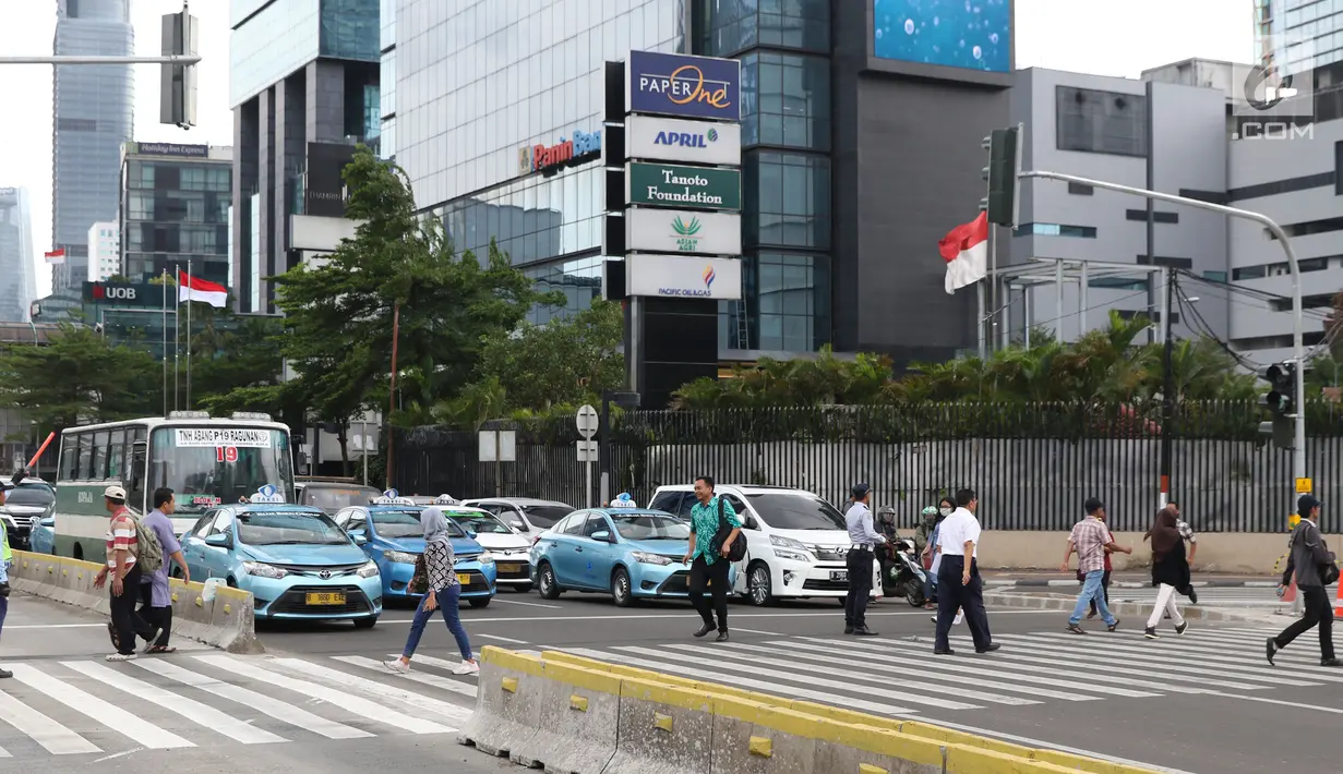 Warga menyebrang jalan Sudirman di kawasan Tosari, Jakarta, Jumat (14/12). Penggunaan pelican crossing di kawasan ini menggantikan fungsi Jembatan Penyebrangan Orang (JPO) Tosari yang akan dibongkar. (Liputan6.com/Helmi Fithriansyah)