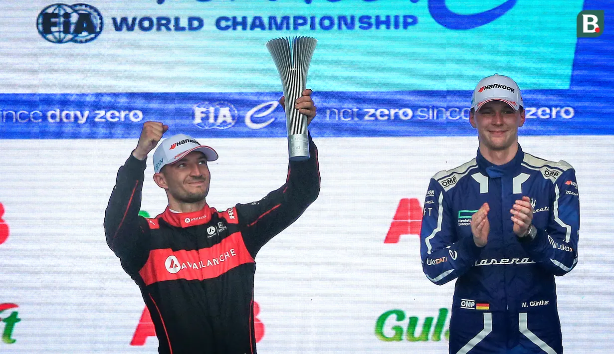 Pembalap Avalanche Andretti, Jake Dennis (kiri) mengangkat trofi kemenangan setelah finis kedua pada balapan Jakarta E-Prix 2023 round-11 di Jakarta International E-Prix Circuit, Ancol, Jakarta, Minggu (04/06/2023). (Bola.com/Bagaskara Lazuardi)