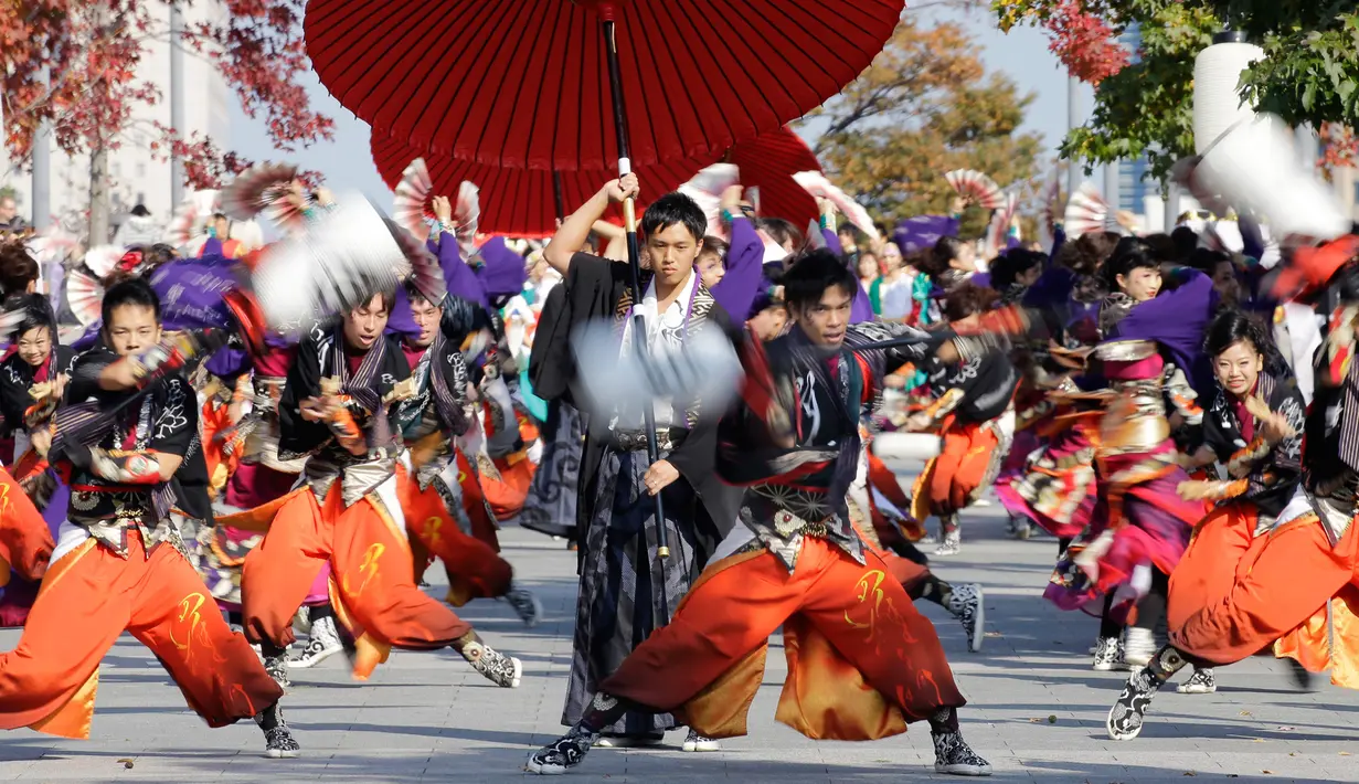 Para penari beraksi membawa payung besar saat tampil dalam pagelaran Festival Yosakoi di Tokyo, Jepang (6/11). Yosakoi sendiri adalah tari dengan ciri khas gerakan tangan dan kaki yang dinamis. (AP Photo/Shizuo Kambayashi)