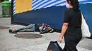 Pejalan kaki melewati seorang pria yang tidur di dekat Penn Station di Madison Square Gardens, New York City, Kamis (17/9/2020). Sejak pandemi virus corona, para tunawisma kini  lebih terlihat seiring banyaknya penutupan banyak tempat penampungan karena alasan kesehatan. (Angela Weiss / AFP)