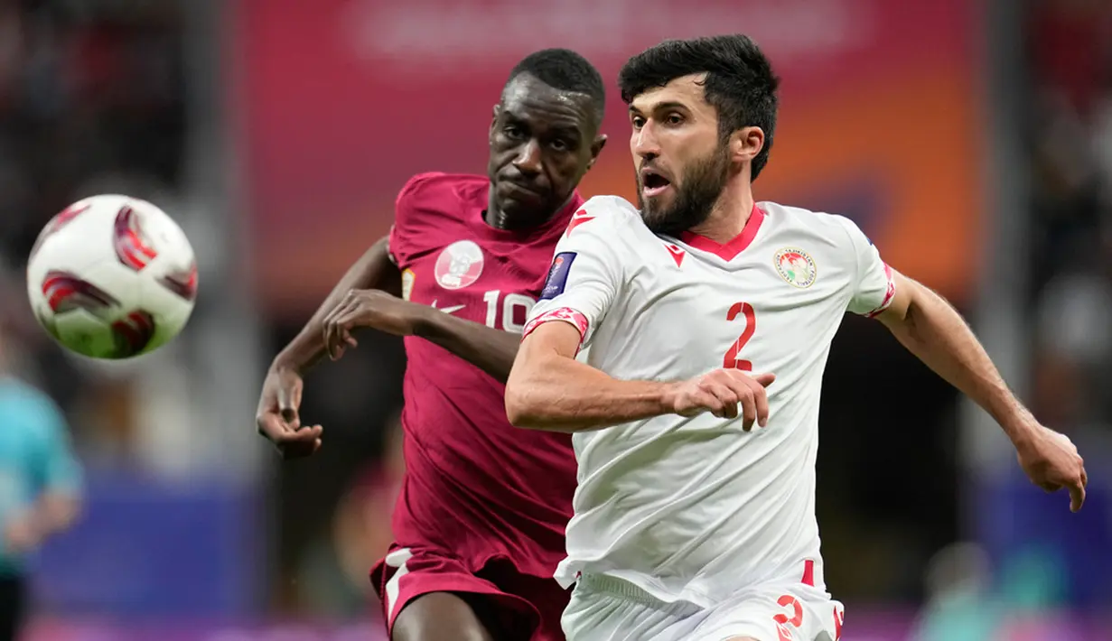Pemain Tajikistan Zoir Dzhuraboev (kanan) dan pemain Qatar Almoez Ali berlari mengejar bola pada pertandingan sepak bola Grup A Piala Asia di Stadion Al Bayt, Al Khor, Qatar, Rabu (17/1/2024). (AP Photo/Aijaz Rahi)