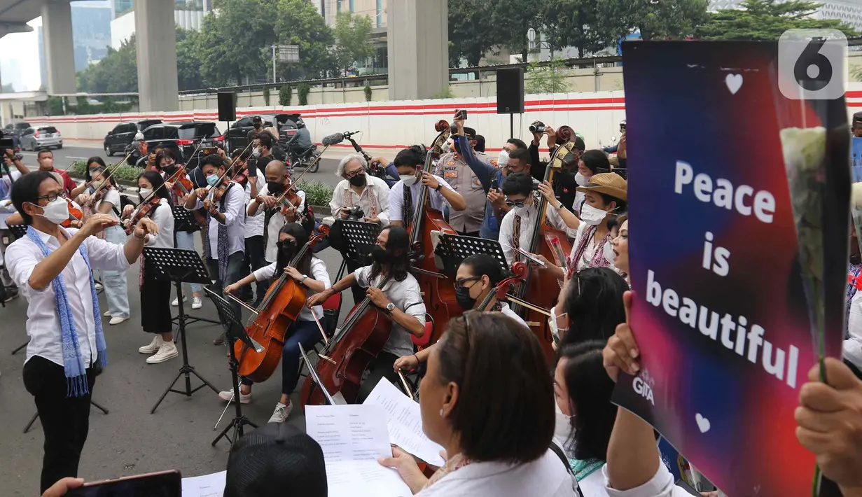Komposer Addie MS memimpin penampilan orkestra saat aksi seruan damai di depan Kedutaan Besar Federasi Rusia, Jakarta, Rabu (30/3/2022). Aksi tersebut mengangkat tema "Setangkai Kembang dan Satu Nyanyian" dengan membawakan lagu Rayuan Pulau Kelapa versi bahasa Rusia. (Liputan6.com/Herman Zakharia)