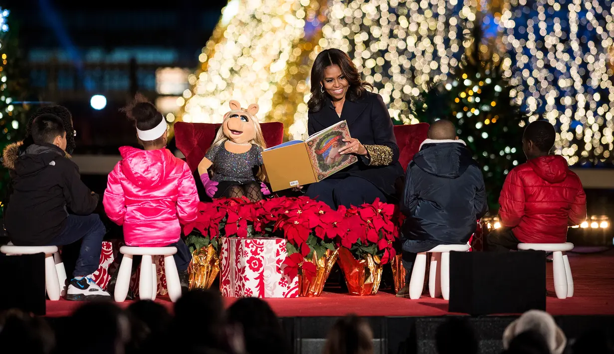 Ibu Negara AS, Michelle Obama membacakan dongeng bersama tokoh boneka Miss Piggy untuk anak-anak dalam acara menyalakan Pohon Natal Nasional di Taman Ellipse, dekat Gedung Putih, Washington, Kamis (3/12). (AFP PHOTO/Brendan SMIALOWSKI)