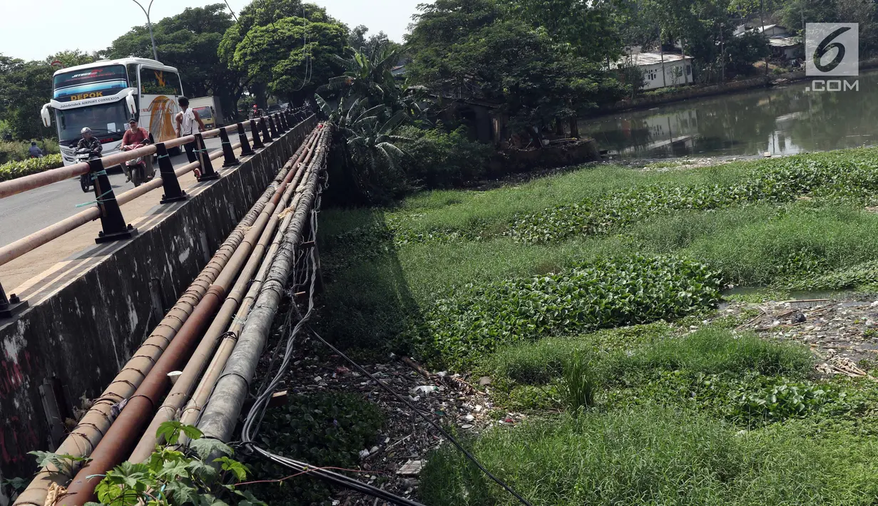 Warga dan pengendara melintasi jembatan di sisi Situ Pengarengan, Kota Depok, Jawa Barat, Kamis (18/4). Tumpukan sampah dan tanaman eceng gondok terlihat menumpuk menutupi permukan air Situ Pengarengan. (Liputan6.com/Helmi Fithriansyah)