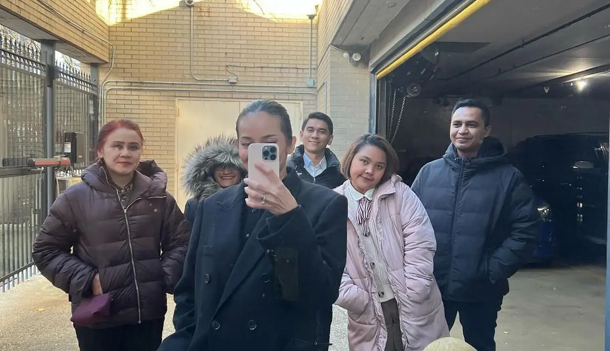 Di foto lainnya memperlihatkan Enzy Storia mengambil mirror selfie mengenakan long coat hitam berkancing yang membalut tubuhnya dengan amat baik karena siluet strukturnya. [Foto: Instagram/enzystoria]