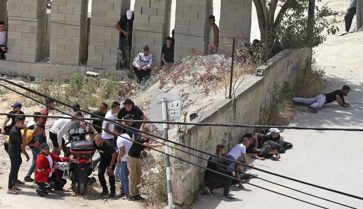 Warga Palestina berlindung selama bentrokan dengan pasukan keamanan Israel di kota Jenin, Tepi Barat, pada 13 Mei 2022. - Seorang warga Palestina terluka oleh tembakan Israel selama operasi di kota Jenin di Tepi Barat yang diduduki utara, kata kantor berita Palestina Wafa. (AFP/JAAFAR ASHTIYEH)