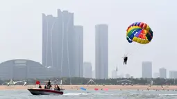 Pengunjung menaiki parasut saat menikmati waktu bersantai di sebuah pantai di Rizhao, Provinsi Shandong, China timur (8/7/2020). (Xinhua/Wang Kai)