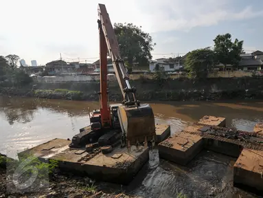 Alat berat melakukan pengerukan tumpukan sisa lumpur dan tanah yang menumpuk di pinggir kali Ciliwung, Jakarta, Kamis (28/7). Tumpukan tanah dan lumpur sisa dari pengerukan kali Ciliwung mulai dibersihkan.(Liputan6.com/Yoppy Renato)