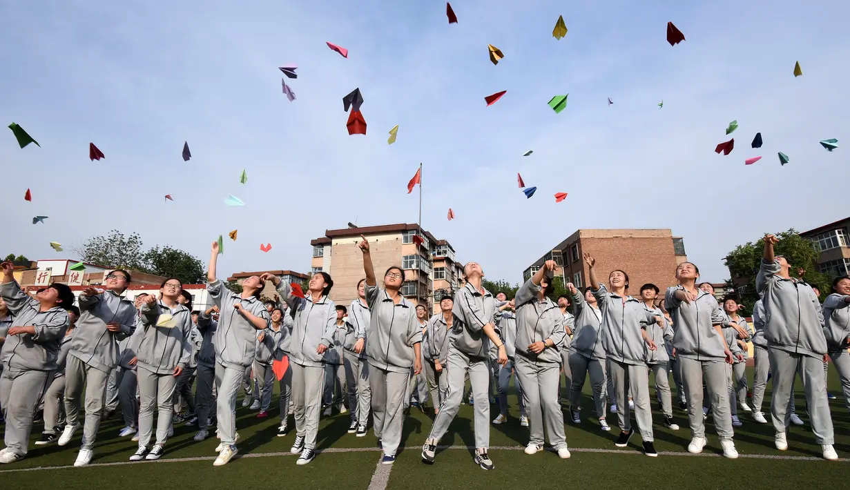 Para siswa SMA melempar pesawat-pesawatan kertas sebelum mengikuti ujian masuk perguruan tinggi di sebuah sekolah di Handan, Provinsi Hebei China utara (24/5). (AFP PHOTO/STR)